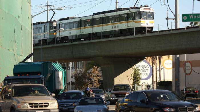 A busy street with the metro rail passing over head.