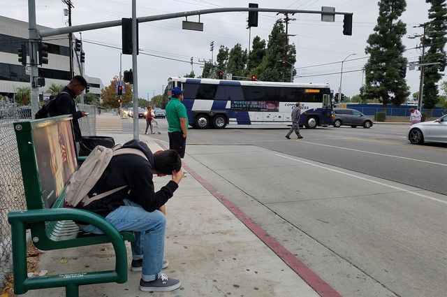 People waiting for a bus at an intersection.