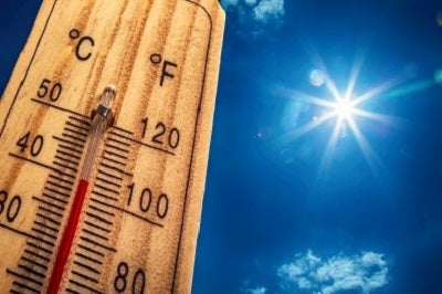 A thermometer with a sunny sky in the background.