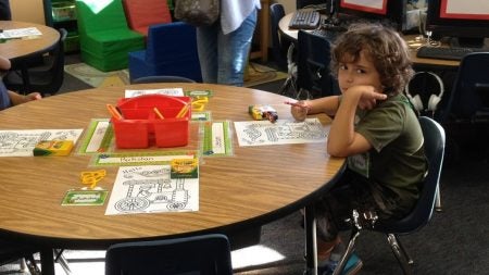young student coloring at a table
