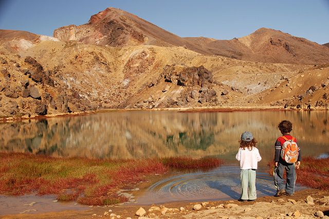 Two children standing in front of a body of water.