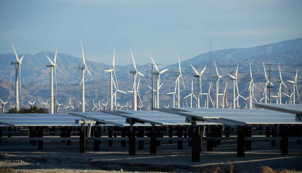 Giant wind turbines are powered by strong winds in front of solar panels on March 27, 2013 in Palm Springs, California.