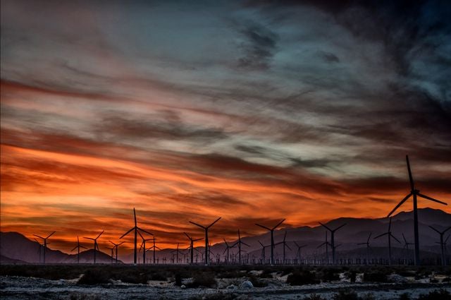 A view of a windmill farm during the sunset.