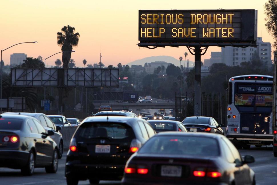 In this Friday, Feb. 14, 2014, file photo, morning traffic makes its way toward downtown Los Angeles along the Hollywood Freeway past an electronic sign warning of severe drought.