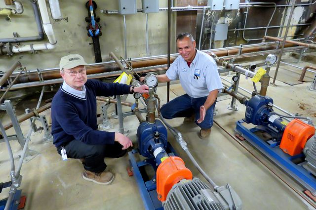 Two men squatting near a device.