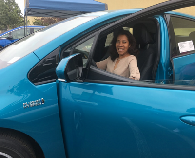person sitting in a car with the driver's door open