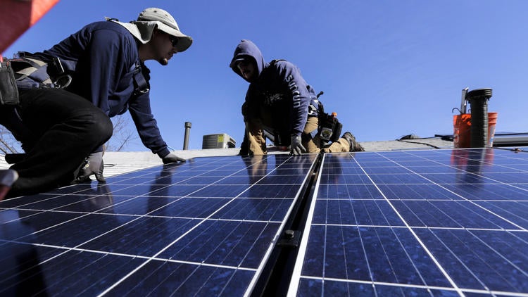 George Gonzalez, left, and Hector Maldonado, crew from Sunrun home solar company, install a solar system on home in Van Nuys on Feb. 4, 2016.