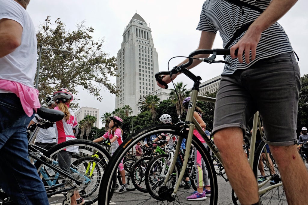 Cyclists make their way through an intersection past City Hall in downtown Los Angeles on Sunday, Oct. 18, 2015