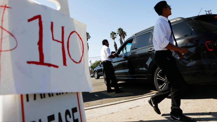 A sign that reads "$140" in a parking lot, a car is next to the sign.