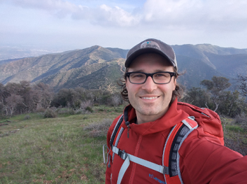 Photo of UCLA postdoctoral researcher Joscha Beninde in front of a mountain landscape