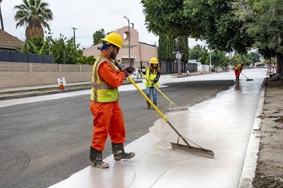 City workers apply a cooling paint on roads in Pacoima, part of Los Angeles’ strategy to combat climate change