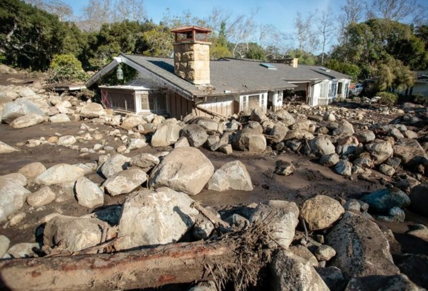 A house covered in rocks and mud from a landslide.