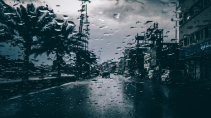 a view of a street through a window covered with rain drops