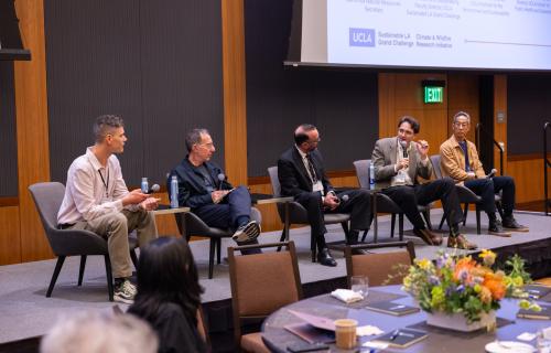 A panel of people talking while sitting on stagel