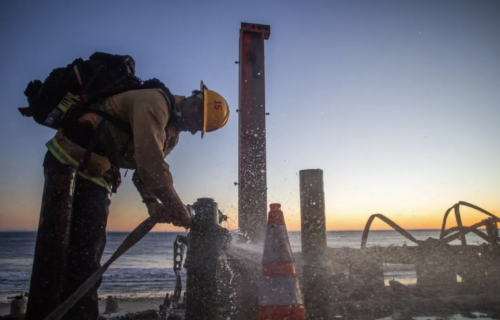 A firefighter connects a hose to hydrant.