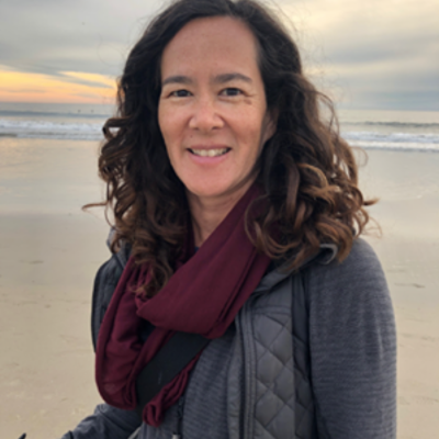 A woman on the beach smiling at the camera.