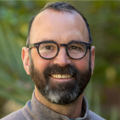 A man with glasses smiling at the camera