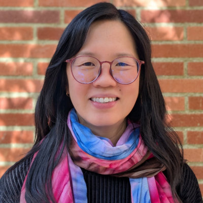 A woman with glasses smiles at the camera.