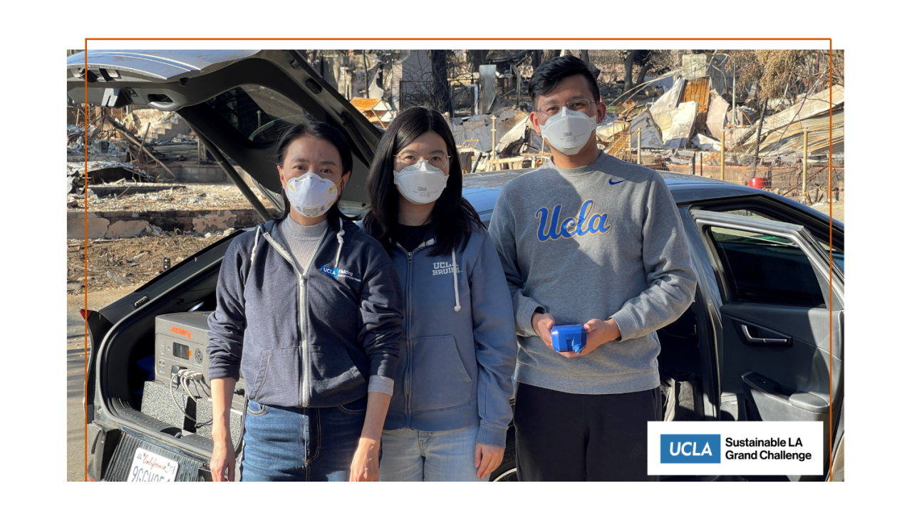 Three people wearing facemasks standing in front of a car with debris from the Palisades Fire behind them.