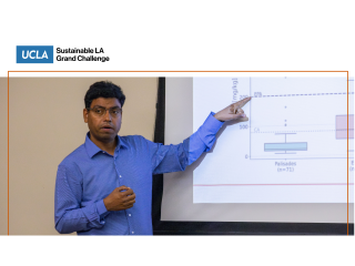 A man gestures at a chart projected on the screen behind him.