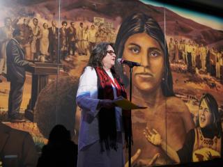 Judith Baca speaking in front of "La Memoria de la Tierra: UCLA"
